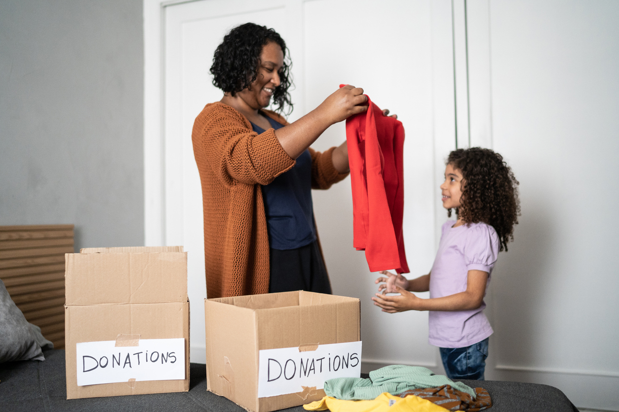 Mother and daughter sorting out clothes in boxes to donate at home