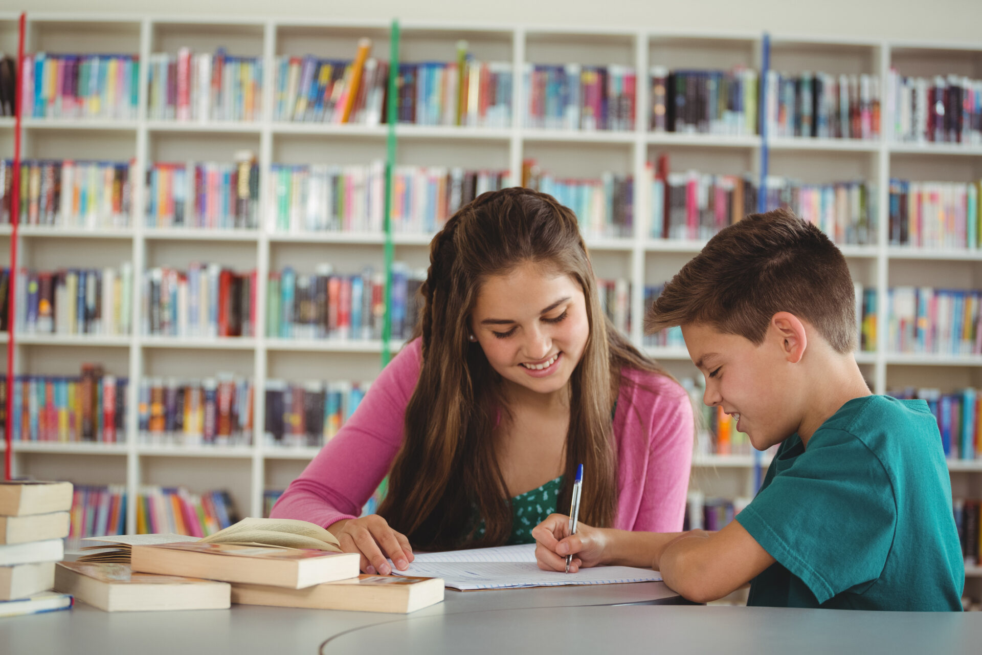 Smiling school kids doing homework in library at school